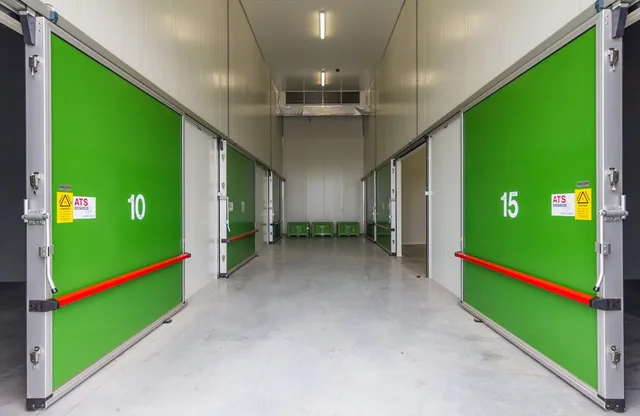 Numbered green sliding doors of cold stores along a bright white corridor