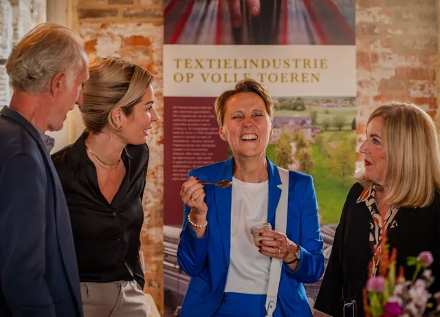 Four guests sharing a laugh at a textile industry exhibition opening